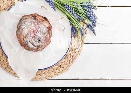 Torta di Pasqua sul piatto e fiori su sfondo di legno Foto Stock