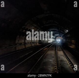 Un treno che si avvicina nel tunnel con le luci accese Foto Stock