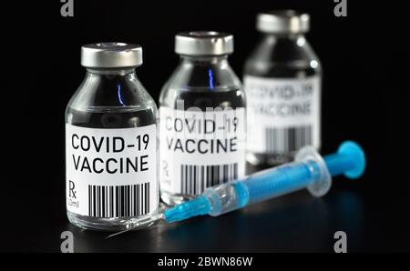 Vaccino Coronavirus Covid-19 Concept - tre fiale di vetro su tavolo nero, siringa blu vicino al closeup dettaglio (design proprio - codice a barre fittizio) Foto Stock