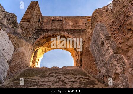 Arco di pietra - la luce del sole serale splende su un arco di pietra in cima all'antica parete alta del Colosseo. Roma, Italia. Foto Stock