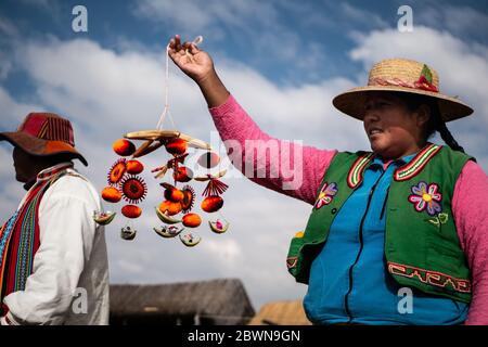 La comunità di Uros mostra i loro artigianato mentre i turisti visitano la loro isola galleggiante fatta di canne di totora al lago Titicaca in Perù. Foto Stock