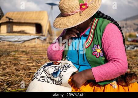 La comunità di Uros mostra i loro artigianato mentre i turisti visitano la loro isola galleggiante fatta di canne di totora al lago Titicaca in Perù. Foto Stock