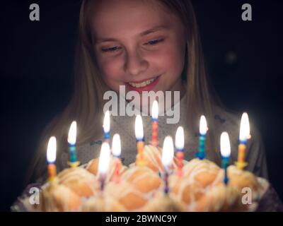 La ragazza adolescente admires candele brucianti alla torta sul suo compleanno. Foto Stock