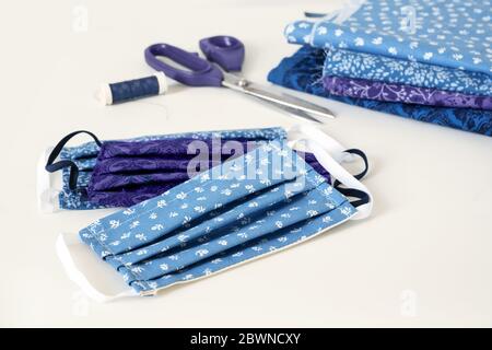 Cucire contro pandemia di coronavirus, maschera di comunità casalinga, forbici, filato e tessuto di cotone su un tavolo bianco, spazio di copia, fuoco selezionato, narr Foto Stock