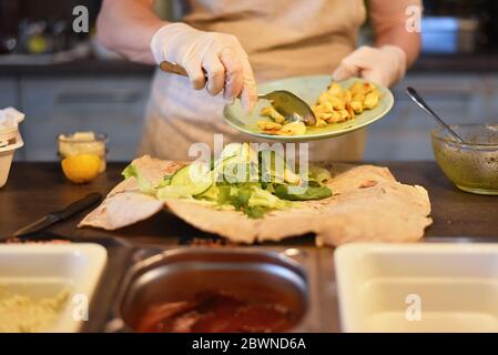 donna riempie e rotola un involucro vegetale Foto Stock