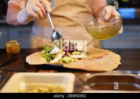 donna riempie e rotola un involucro vegetale Foto Stock