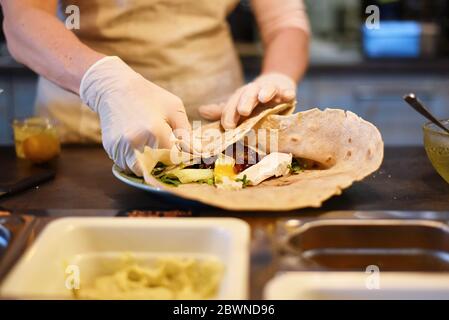 donna riempie e rotola un involucro vegetale Foto Stock