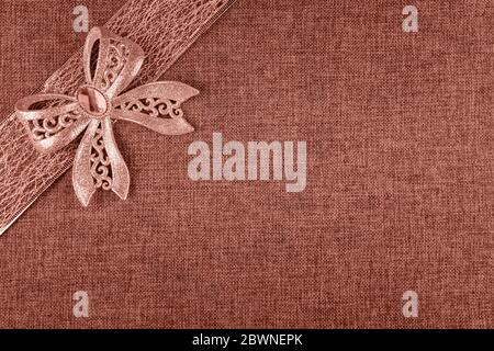 Elegante corallo lucido glitter fiocco legato su nastro corallo colorato e su corallo naturale burlap. Sfondo orizzontale del biglietto di auguri con ampio spazio di copia AN Foto Stock