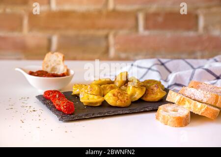 Pelmeni cibo russo, gnocchi di carne fritti su piatto di pietra, con tomati, pane e salsa rossa. Foto Stock