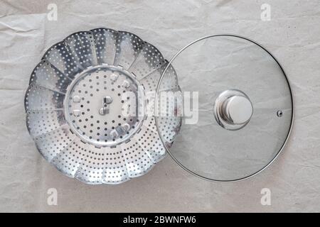 Inserto in acciaio per cottura in alimenti, con coperchio in padella, su carta grigia. Foto Stock