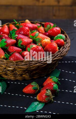 Fragole succose disposte in ciotola di rattan su un corridore del tavolo Foto Stock