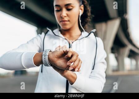 Primo piano della mano della donna con un orologio intelligente. Dopo l'esercizio, fit woman che guarda sull'activity tracker. Foto Stock