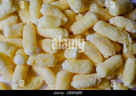 Croccanti ariosi, polsini di mais, spuntini di puffcorn sfondo. Shot dettagliato di puffcorn pronto per il consumo. Dolci croccanti. Foto Stock