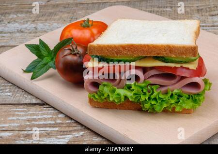Un delizioso panino con salsiccia, formaggio, pomodori e lattuga. Foto Stock