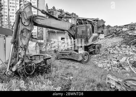 Escavatore prima di demolire il vecchio edificio. Ricostruzione della città. Bianco e nero Foto Stock