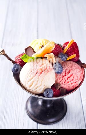 Trio di gustoso gelato da dessert congelato al limone, alla vaniglia e alla fragola in una ciotola metallica con frutti di bosco Foto Stock