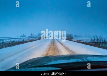 Strada di campagna al crepuscolo durante una bizzarda nel Michigan centrale, Stati Uniti Foto Stock