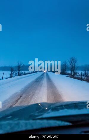 Strada di campagna al crepuscolo durante una bizzarda nel Michigan centrale, Stati Uniti Foto Stock