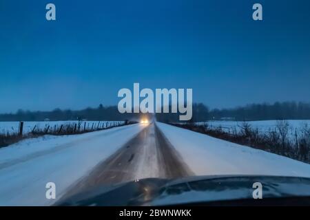 Strada di campagna al crepuscolo durante una bizzarda nel Michigan centrale, Stati Uniti Foto Stock