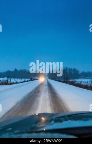 Strada di campagna al crepuscolo durante una bizzarda nel Michigan centrale, Stati Uniti Foto Stock