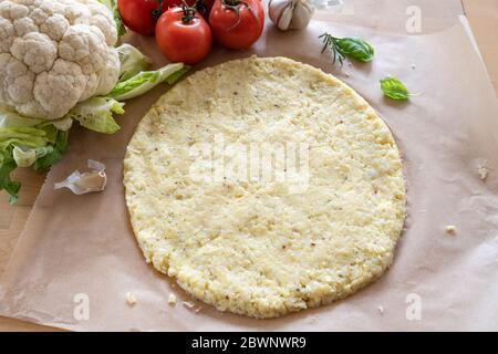 Pizza base vegetale da cavolfiore grattugiato e formaggio su carta da forno, sana alternativa per carb basso e dieta chetogena, vista dall'alto, sele Foto Stock