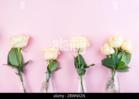 Bella beige taglio fresco Rose in vaso di vetro su sfondo rosa. Composizione floreale minima per regalo romantico, posa piatta Foto Stock
