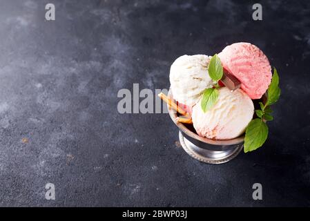 Cucchiai e sapori colorati di gelato con menta su fondo di pietra Foto Stock