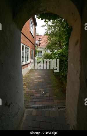 Vista attraverso uno stretto corridoio in un piccolo vicolo residenziale, tipico nel centro storico medievale di Lubecca, Germania, fuoco selezionato Foto Stock