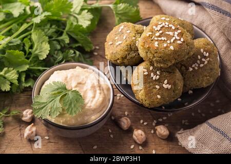 Falafel di ceci fatti in casa con coriandolo in una ciotola su sfondo di legno Foto Stock