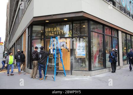 I lavoratori riparano e salgono le vetrine dei negozi presso Urban Outfitters in Herald Square dopo che i vandali e i saccheggiatori usano le proteste per la morte di George Floyd come opportunità per causare caos. Manhattan, New York City, USA 2 giugno 2020 Foto Stock