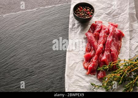 Pezzi di carne di manzo fresca con spezie su sfondo scuro Foto Stock