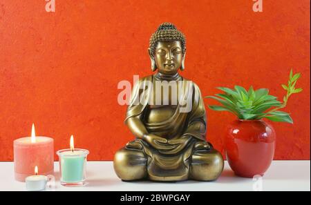 La statua di Buddha contro uno sfondo arancione della parete evoca una sensazione di pace, calma e tranquillità. Per interni in stile Zen. Primo piano. Foto Stock