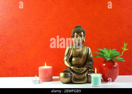 La statua di Buddha contro uno sfondo arancione della parete evoca una sensazione di pace, calma e tranquillità. Per interni in stile Zen, larghi con copia negativa Foto Stock