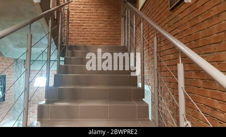 Edificio in mattoni rossi con una moderna scala in stile loft con ringhiera in metallo. Le scale adornano l'edificio. Scala moderna. Ringhiera in acciaio. Scala i Foto Stock