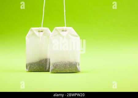 due sacchetti di carta bianca con tè nero su uno sfondo verde chiaro, primi piano. Foto Stock