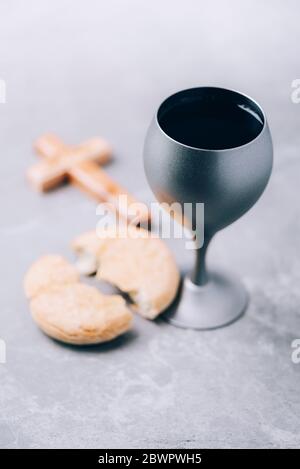 Pane azzimo, calice di vino, croce di legno su fondo grigio. Comunione cristiana per ricordare il sacrificio di Gesù. Pasqua. Eucaristia Foto Stock