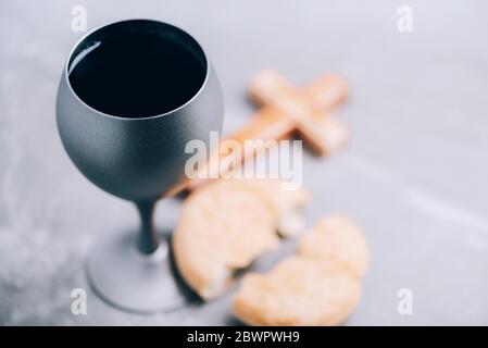 Pane azzimo, calice di vino, croce di legno su fondo grigio. Comunione cristiana per ricordare il sacrificio di Gesù. Pasqua. Eucaristia Foto Stock