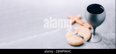 Pane azzimo, calice di vino, croce di legno su fondo grigio. Comunione cristiana per ricordare il sacrificio di Gesù. Pasqua. Eucaristia Foto Stock