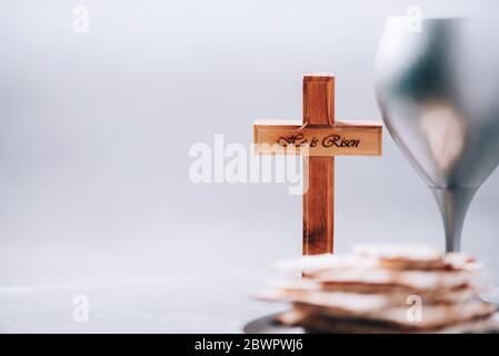 Pane azzimo Matzos, calice di vino, croce di legno su fondo grigio. Comunione cristiana per ricordare il sacrificio di Gesù. Pasqua Foto Stock