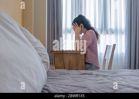 Sensazione di stress e stanchezza. Donna tiene le mani dietro la testa nel luogo di lavoro a casa, su un computer portatile. Foto con messa a fuoco morbida Foto Stock