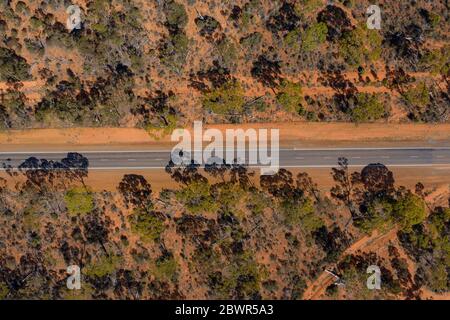 Vista aerea di una lunga strada diritta nell'entroterra australiano desertato rosso nell'Australia occidentale Foto Stock