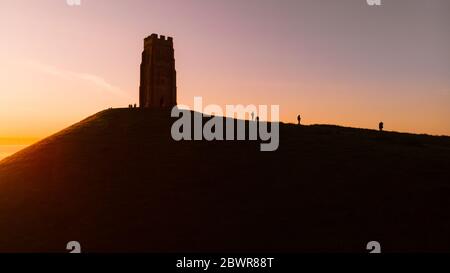 Alba di prima mattina su Glastonbury Tor con sagome di persone, Somerset. Foto Stock