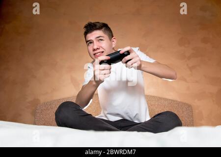 un adolescente è coinvolto in un gioco su una console di gioco. Utilizza un joystick modificato senza contrassegni di identificazione Foto Stock