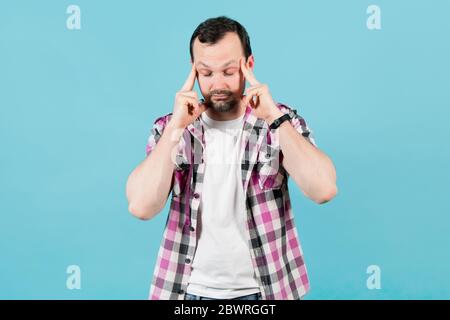 giovane uomo con setole in una camicia di plaid rughe la sua fronte dalla fatica Foto Stock