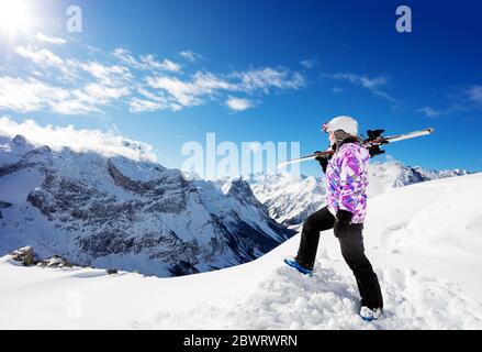 Profilo di una ragazza in cima alla montagna sciatore sportivo stand e tenere lo sci sulla spalla guardare giù in tempo di sole Foto Stock