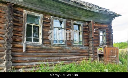 Vecchia casa in legno nella regione di Arkhangelsk, una casa residenziale villaggio in un villaggio forestale, persone abbandonate e a bordo casa. Russia Foto Stock