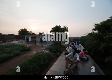 Uomini in cima a un treno sovraffollato che passa attraverso la campagna a Madhya Pradesh, India. Ferrovie indiane. Foto Stock