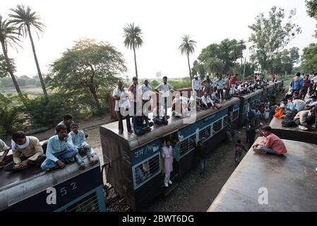 Passeggeri in cima a un treno sovraffollato presso una stazione ferroviaria nella rurale Madhya Pradesh, India. Ferrovie indiane. Foto Stock