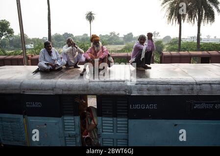 Passeggeri in cima a un treno sovraffollato presso una stazione ferroviaria nella rurale Madhya Pradesh, India. Ferrovie indiane. Foto Stock