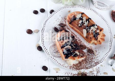 eclair con tazza di caffè e galleggianti su sfondo bianco di legno. San Valentino con colazione Foto Stock